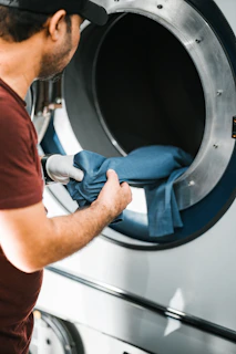 Man putting blue cloth into a washing machine.