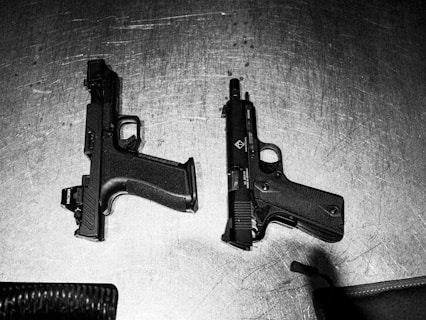 Two handguns are shown on a surface.