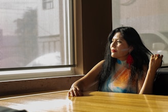 Woman looks out a window, lost in thought.