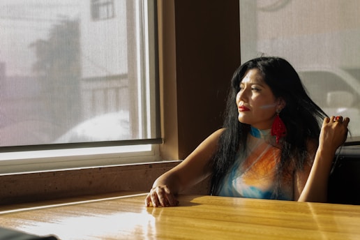 Woman looks out a window, lost in thought.