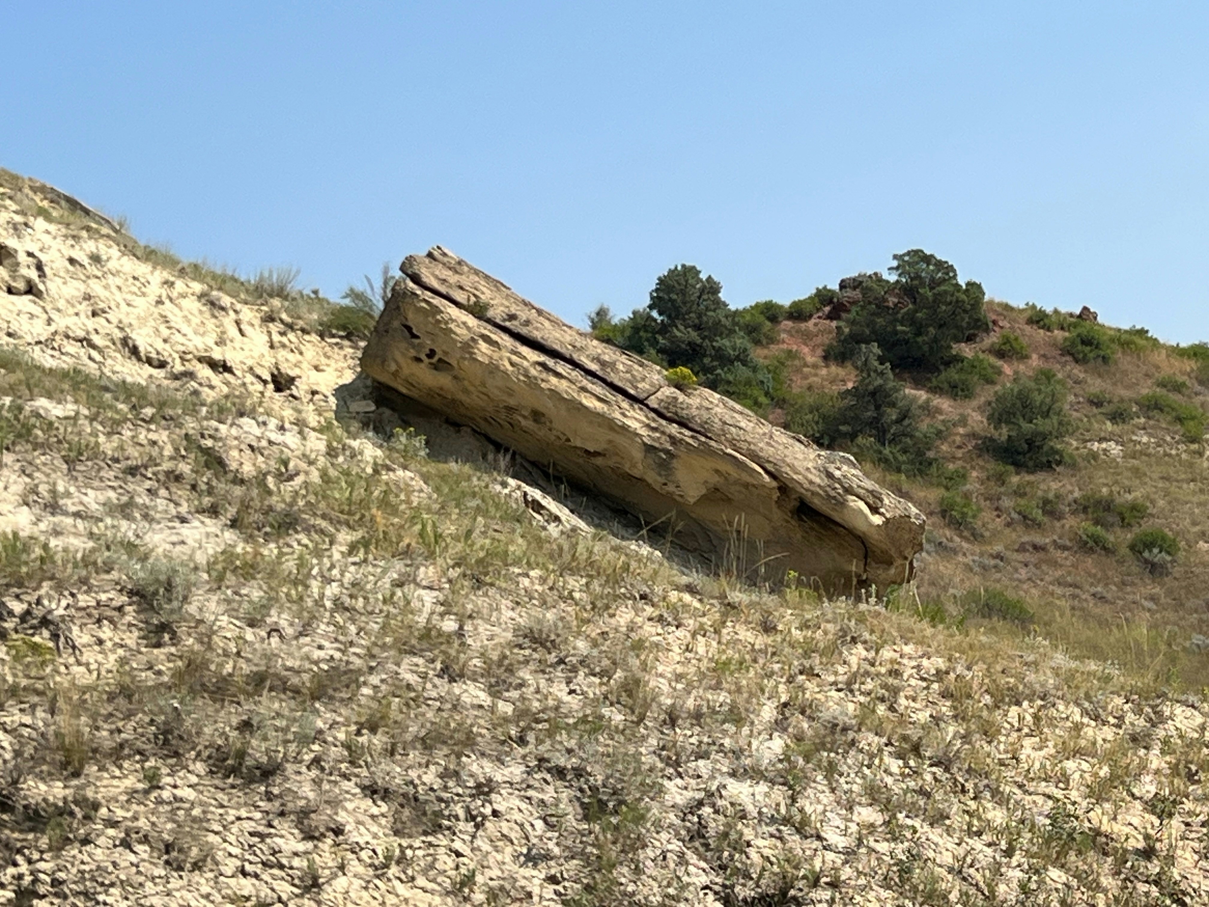 Large rock formation on a grassy hill.