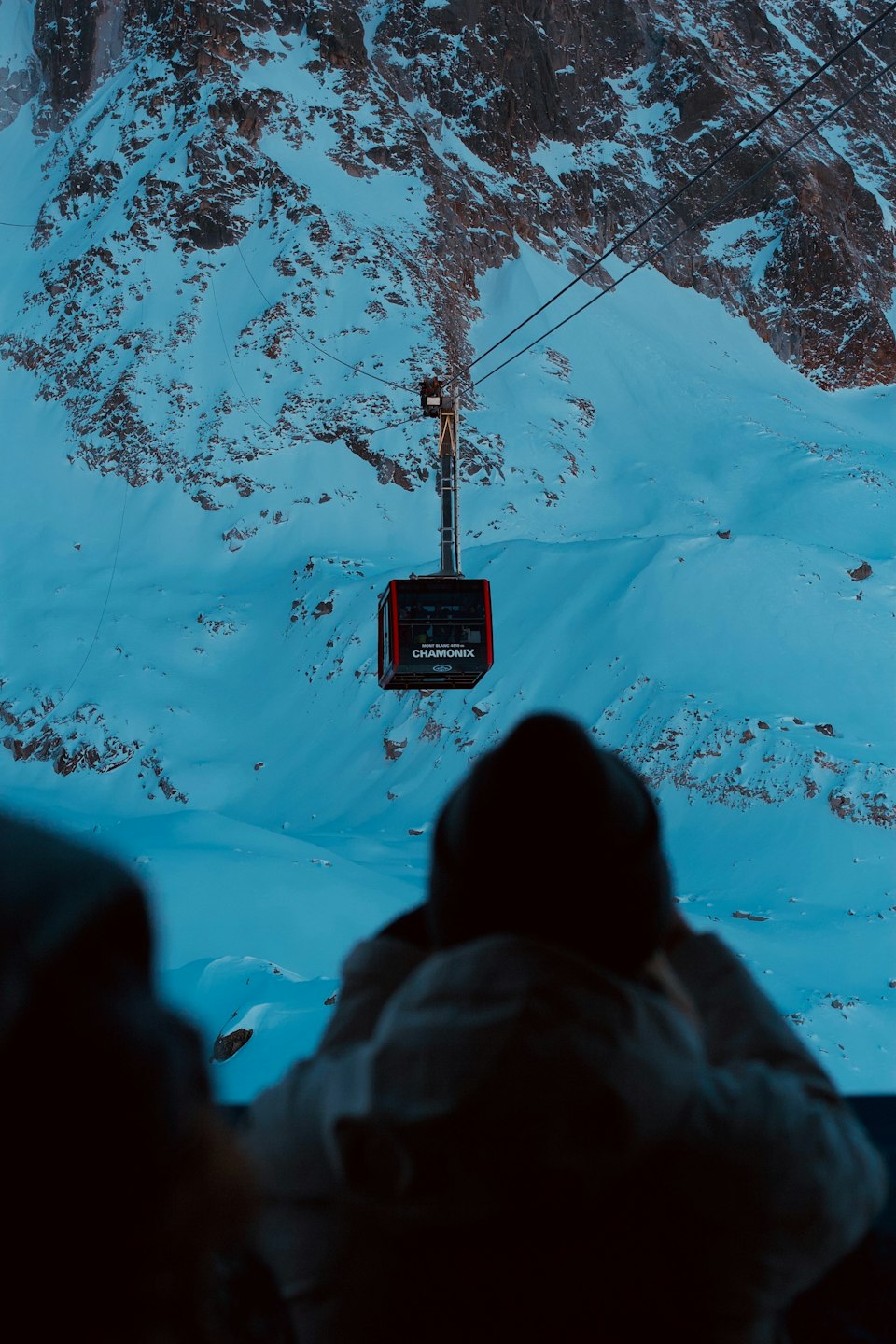 A cable car traveling over snow-covered mountains near the Aiguille du Midi