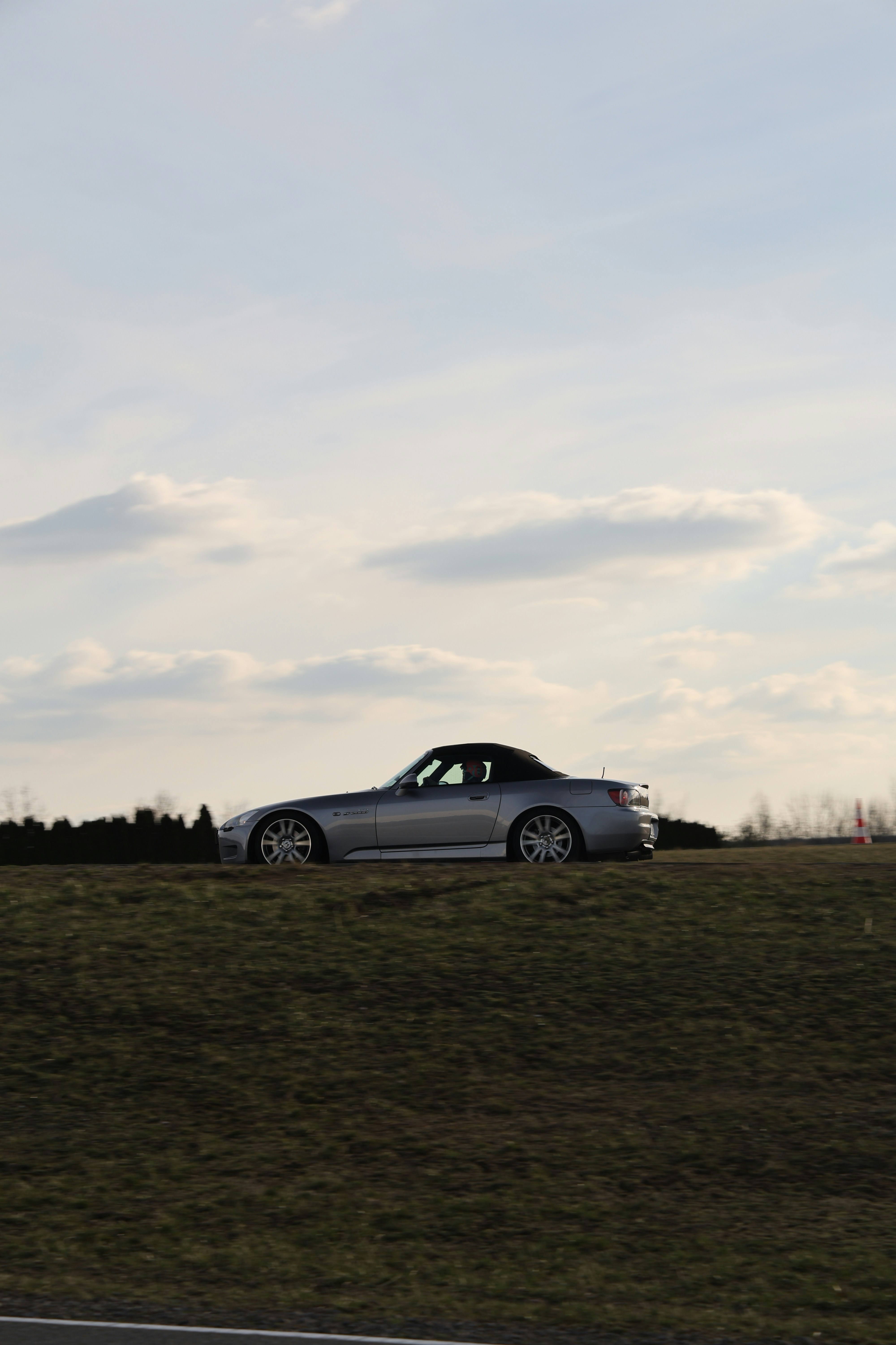 A silver honda s2000 sits outdoors.
