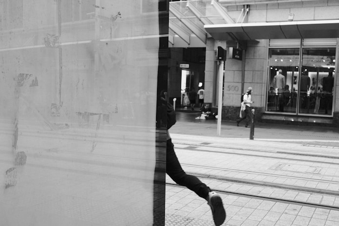 A person walks past a building's reflection.