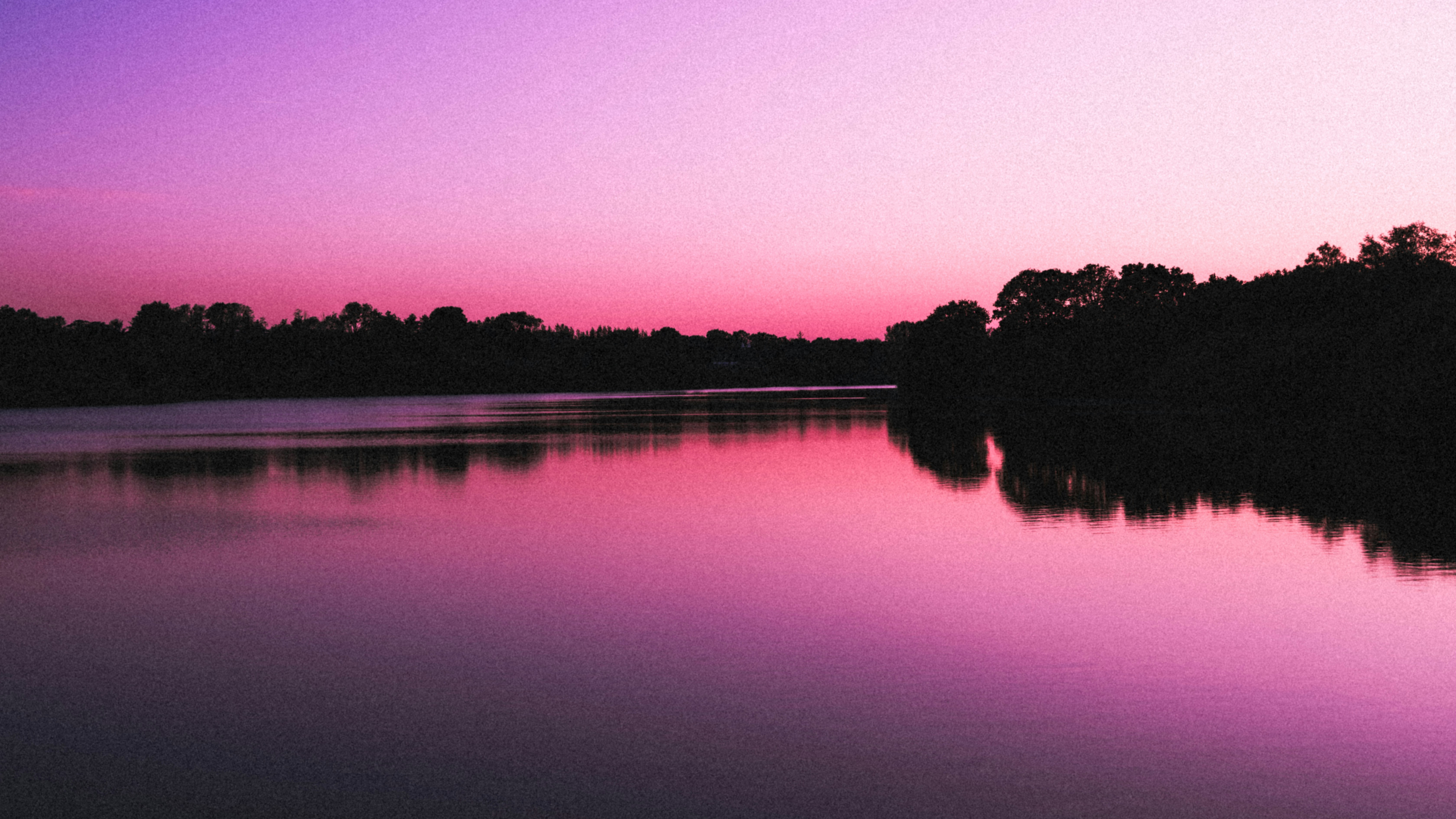 Purple sunset reflects over a calm lake.
