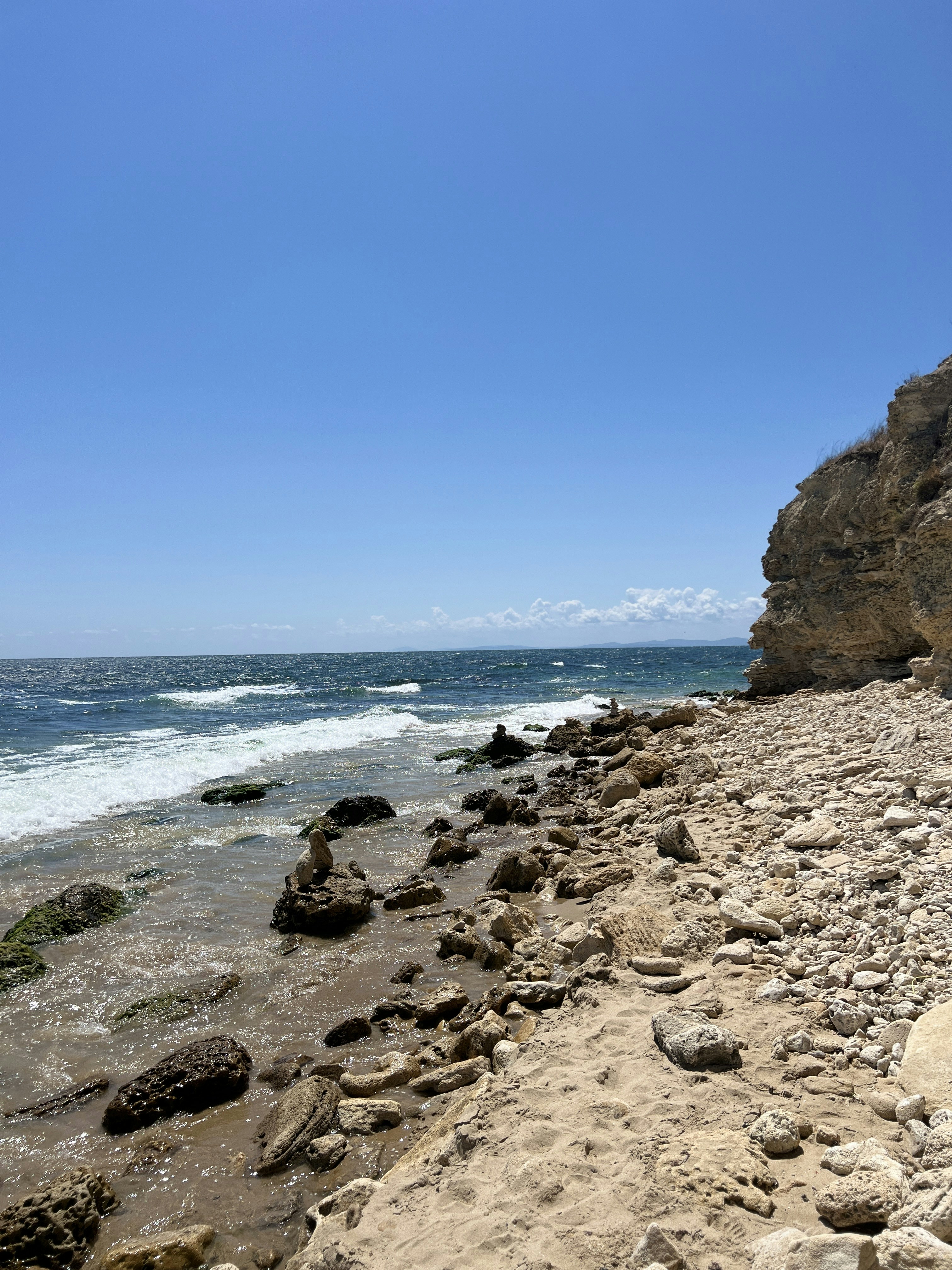 La plage rocheuse rencontre l’océan sous un ciel bleu.