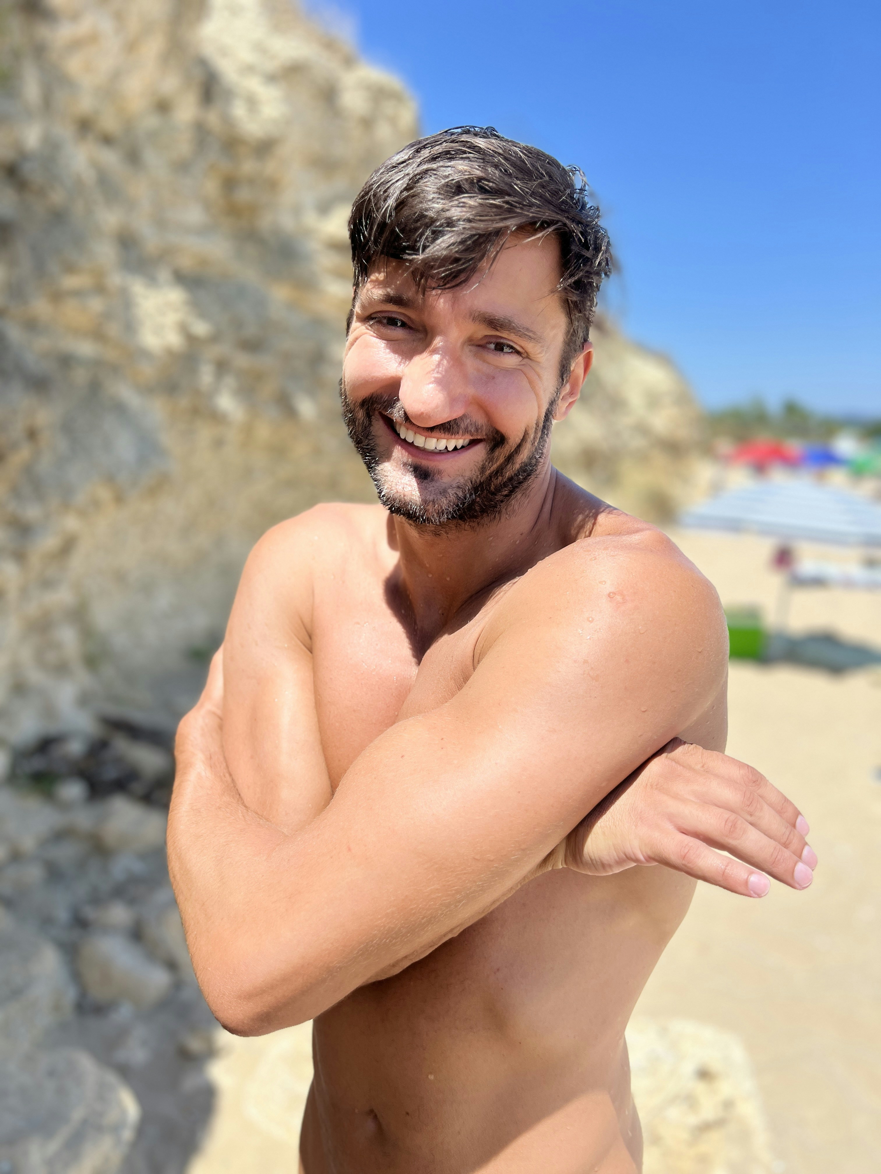 A man is smiling on a sunny beach.