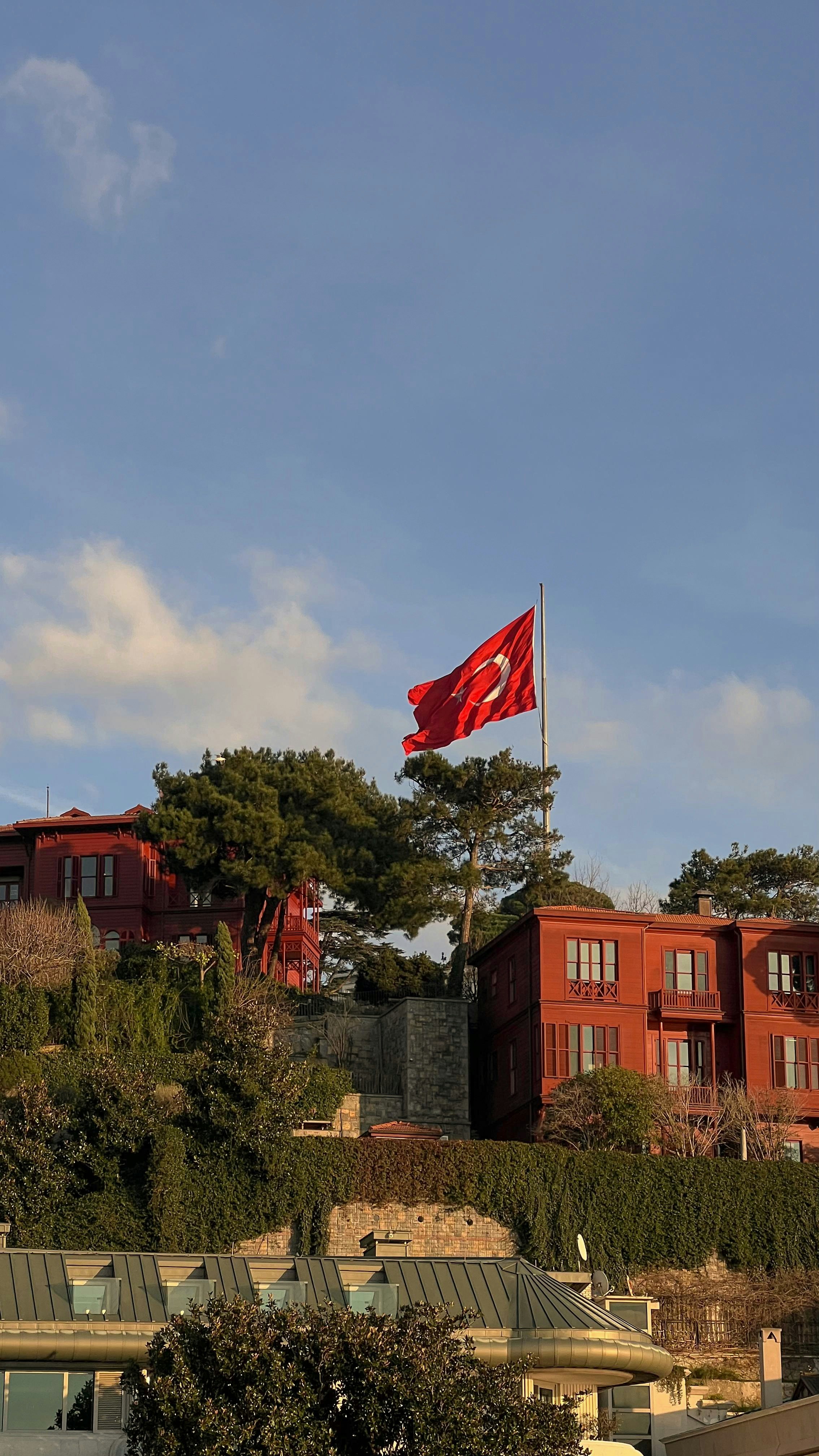 Turkish flag flying over buildings under blue sky.