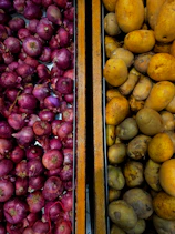 Red onions and potatoes in wooden bins.