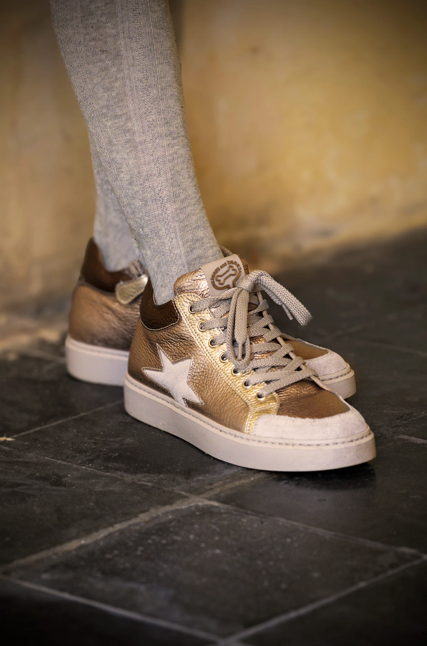 Child wearing small gold sneakers with star details