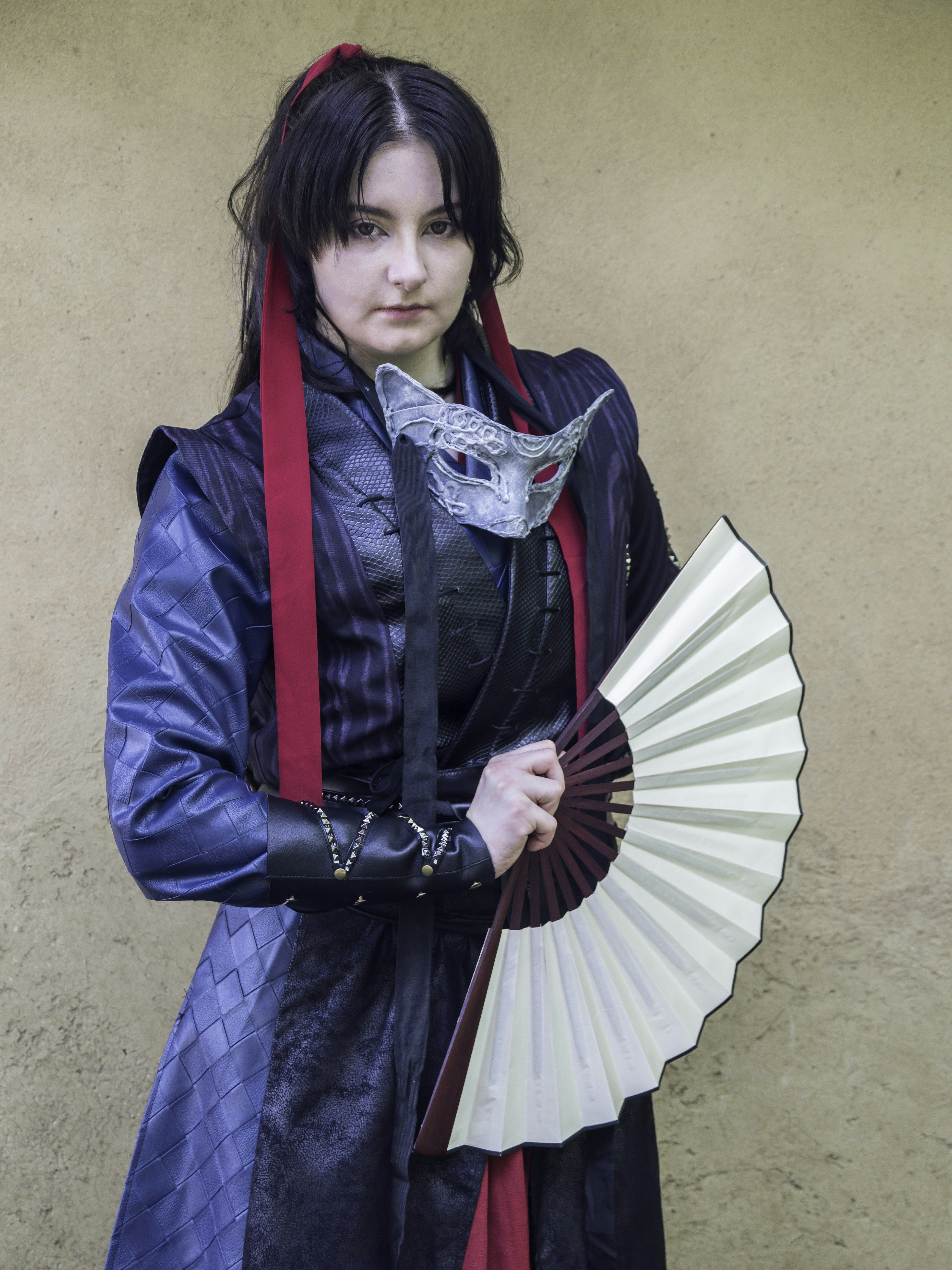 Cosplayer berpose dengan topeng dan kipas.