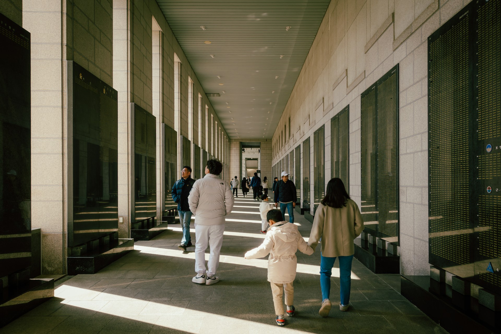 People walk down a long, modern hallway.