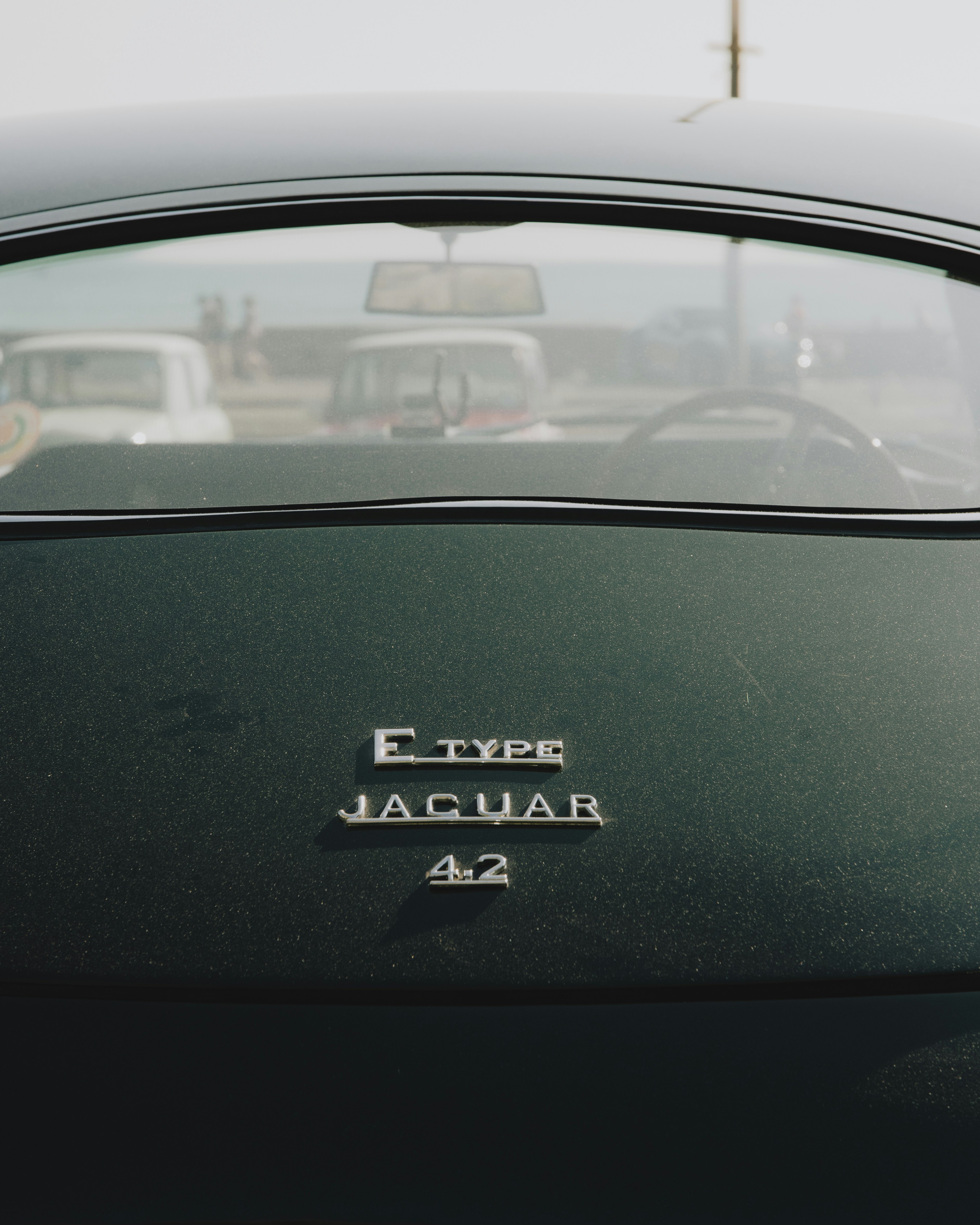 A classic dark green jaguar e-type car.