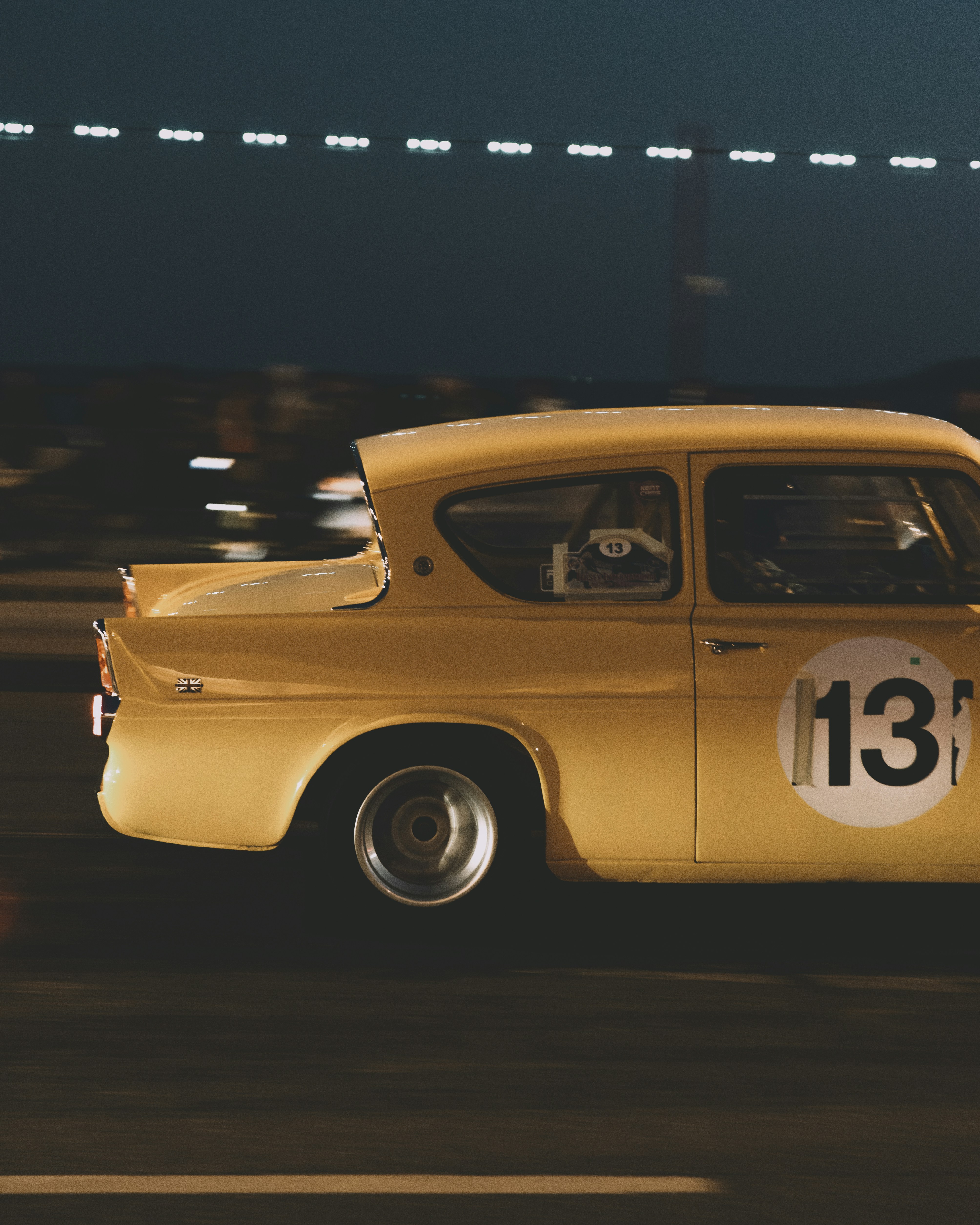A yellow race car speeds at night.