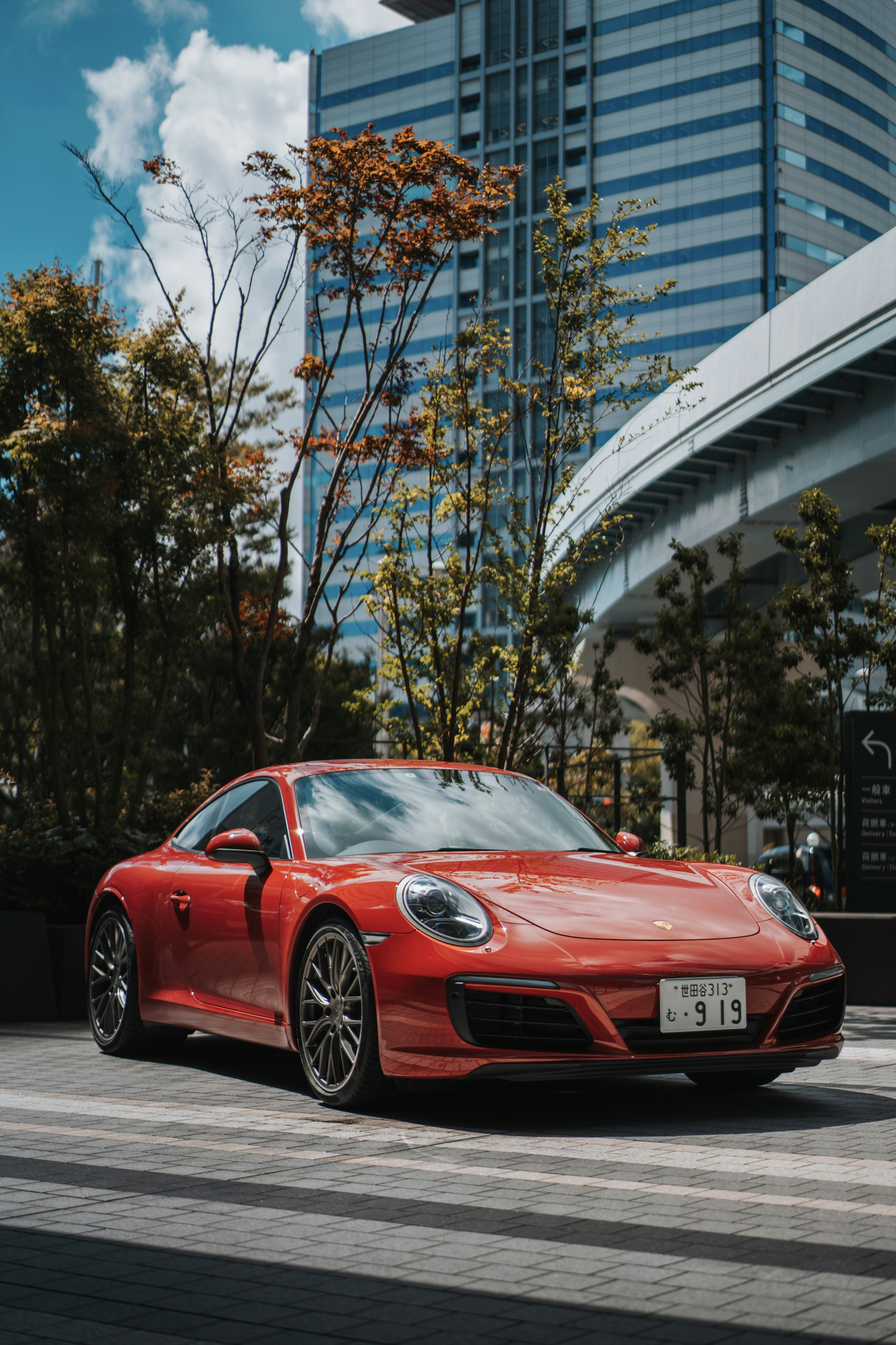 A red porsche is parked in front of buildings.