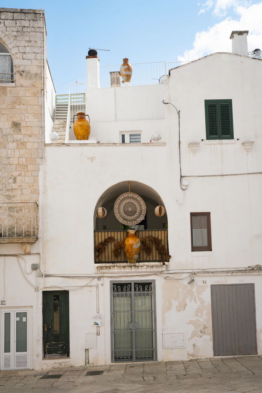 A sunny white street with pottery outside the doors