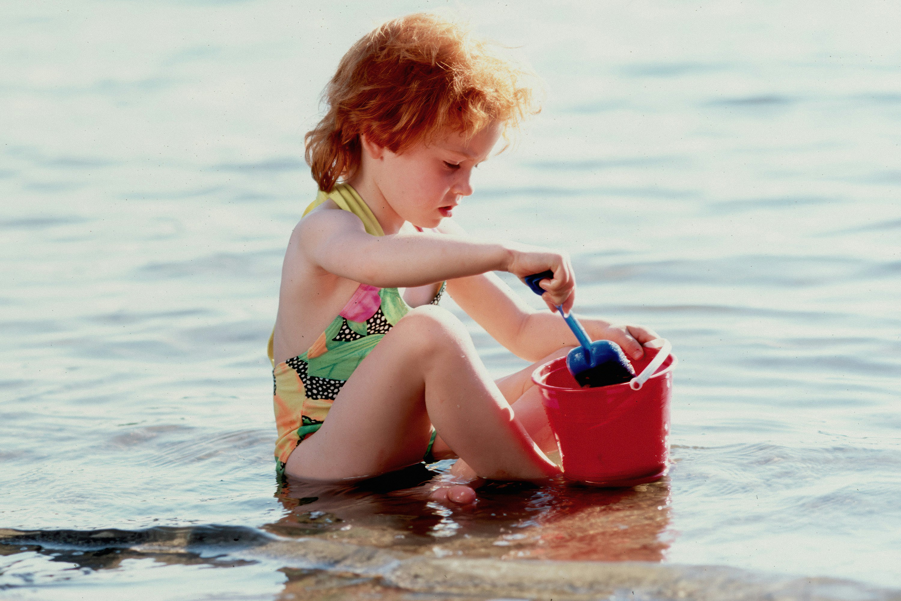 Ragazza giovane con capelli rossi che gioca in acque basse