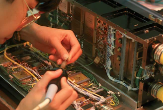 Person working on complex electronic circuitry with wires