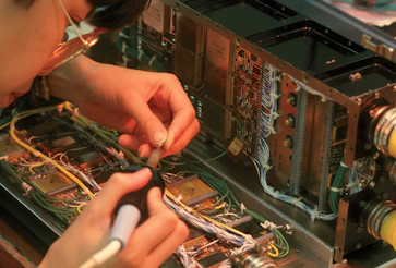 Person working on complex electronic circuitry with wires