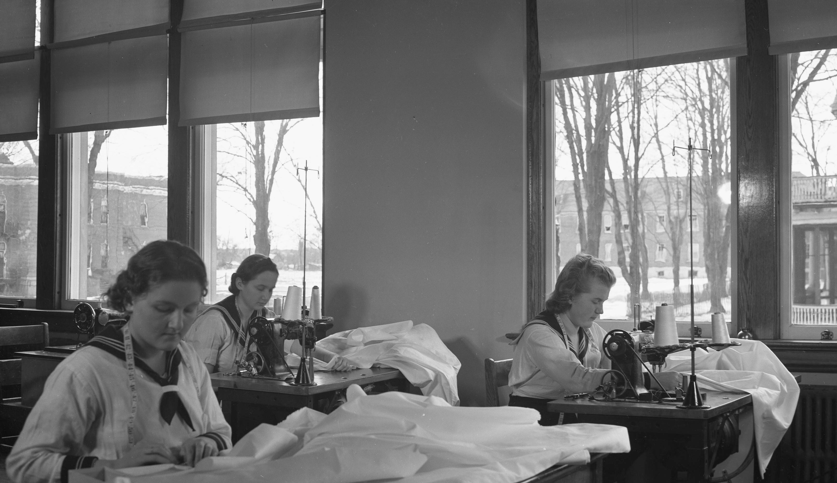 OSD 1938-1939-84 Three young women in school uniforms, using old style sewing machines. One of a series of negatives taken by staff of the Ontario School for the Deaf (now the Sir James Whitney School for the Deaf) in Belleville, Ontario, between 1936 and 1940. Images scanned and donated by Donna Fano in March 2018. Taken circa 1939