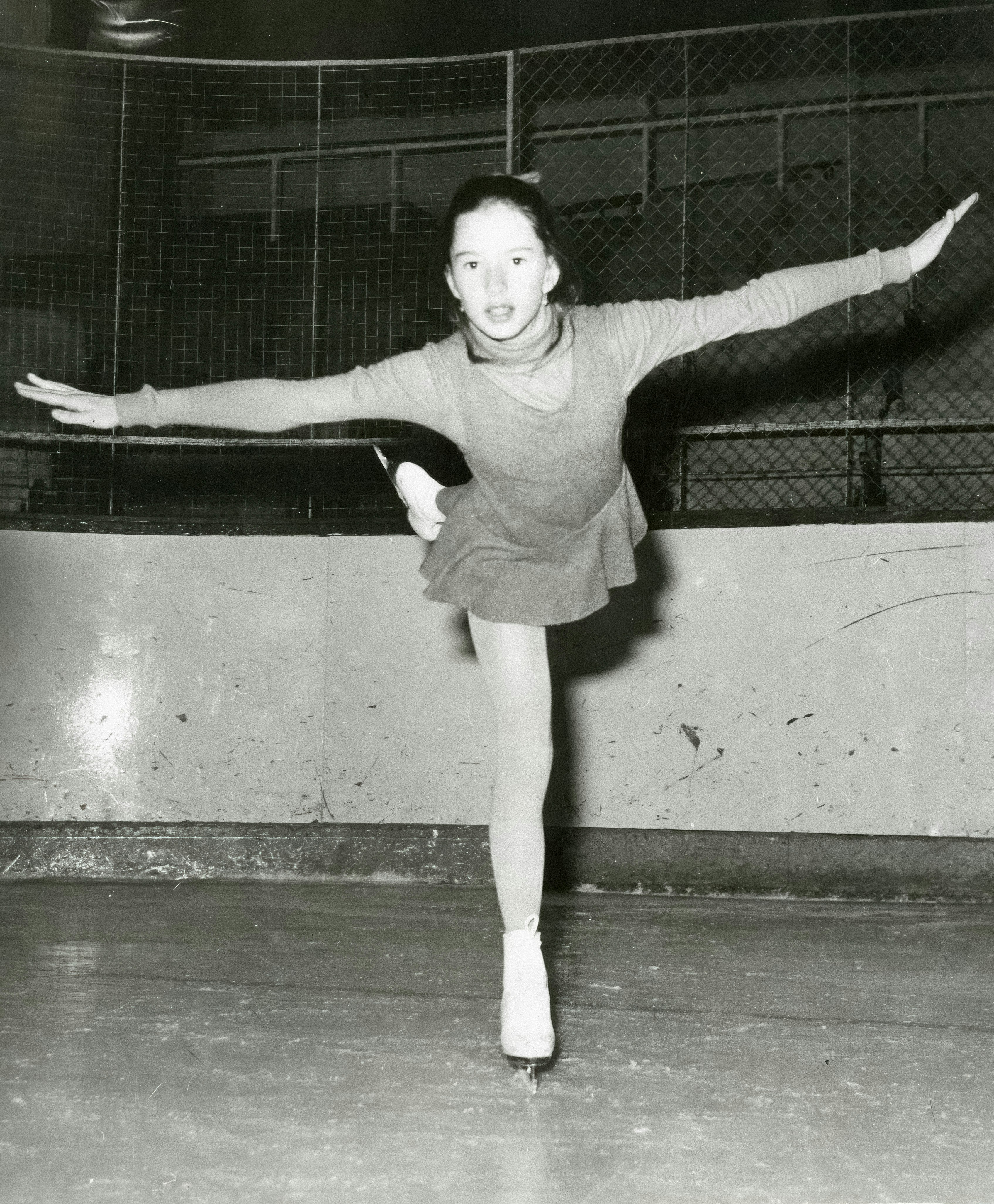 Young figure skater performs a graceful pose on ice