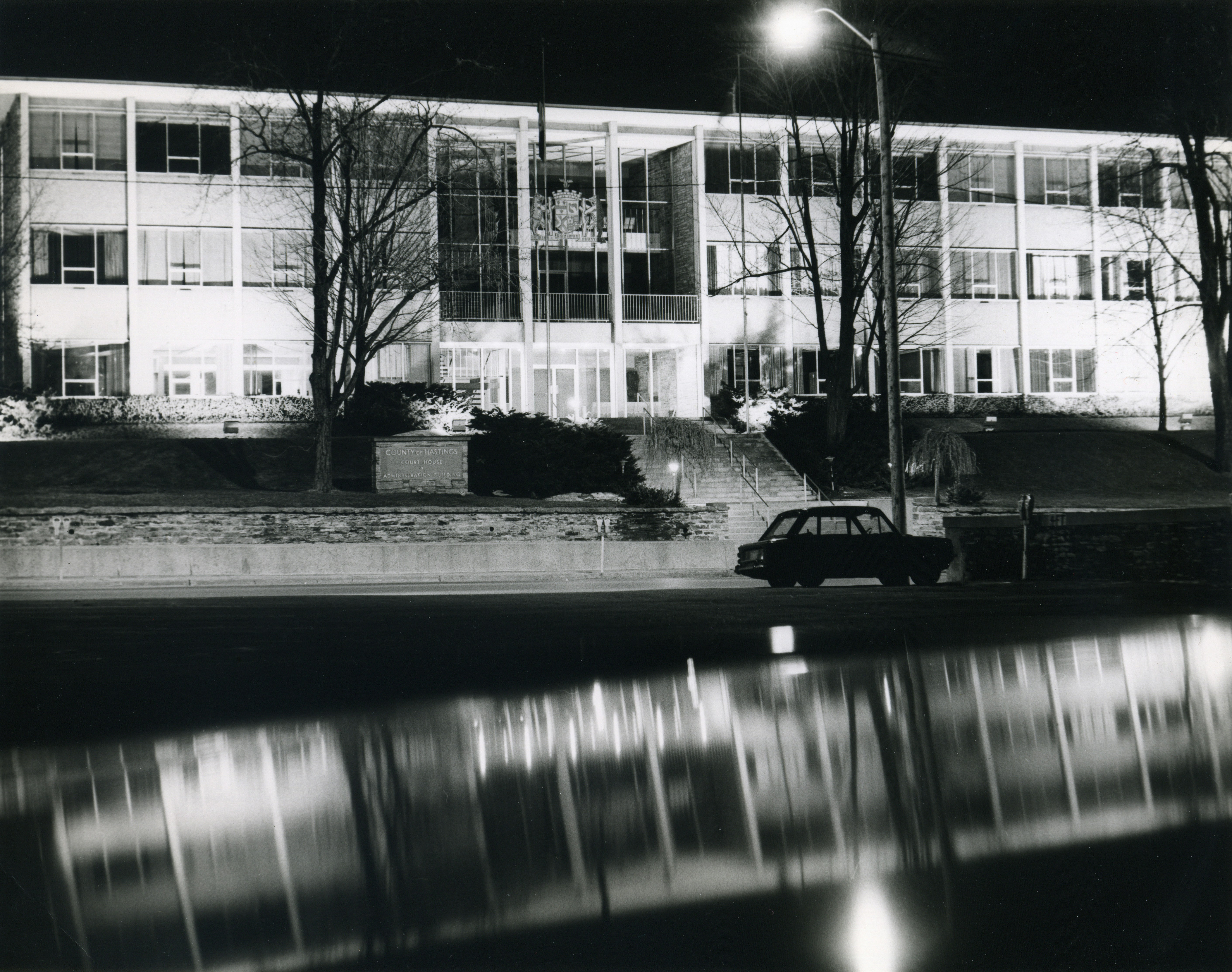 Edificio moderno di notte con auto e riflessi