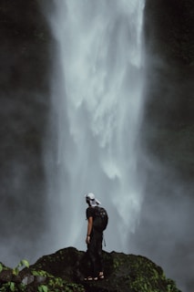 A person stands before a majestic waterfall.