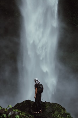 A person stands before a majestic waterfall.