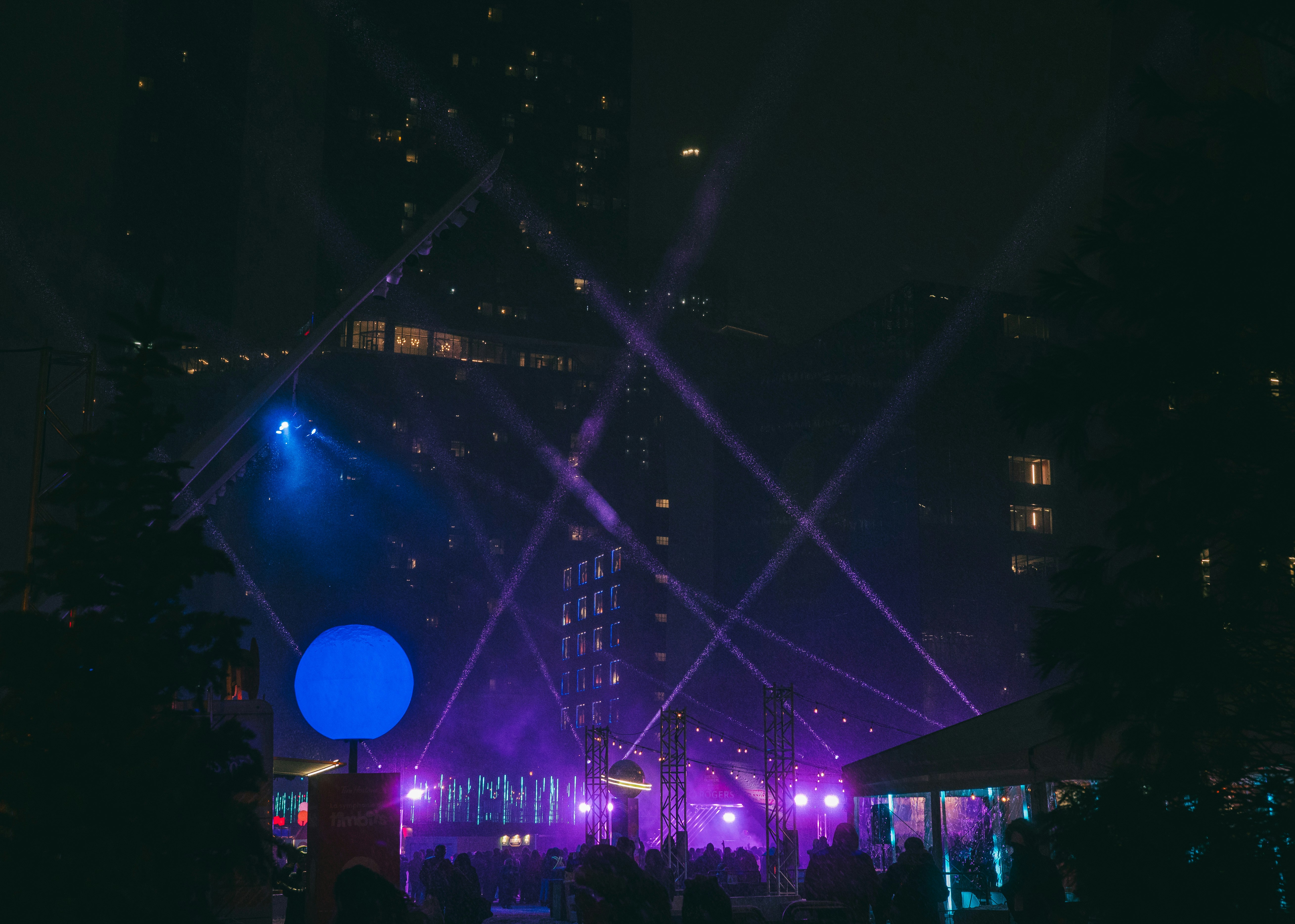 Nighttime light show with purple and blue beams.