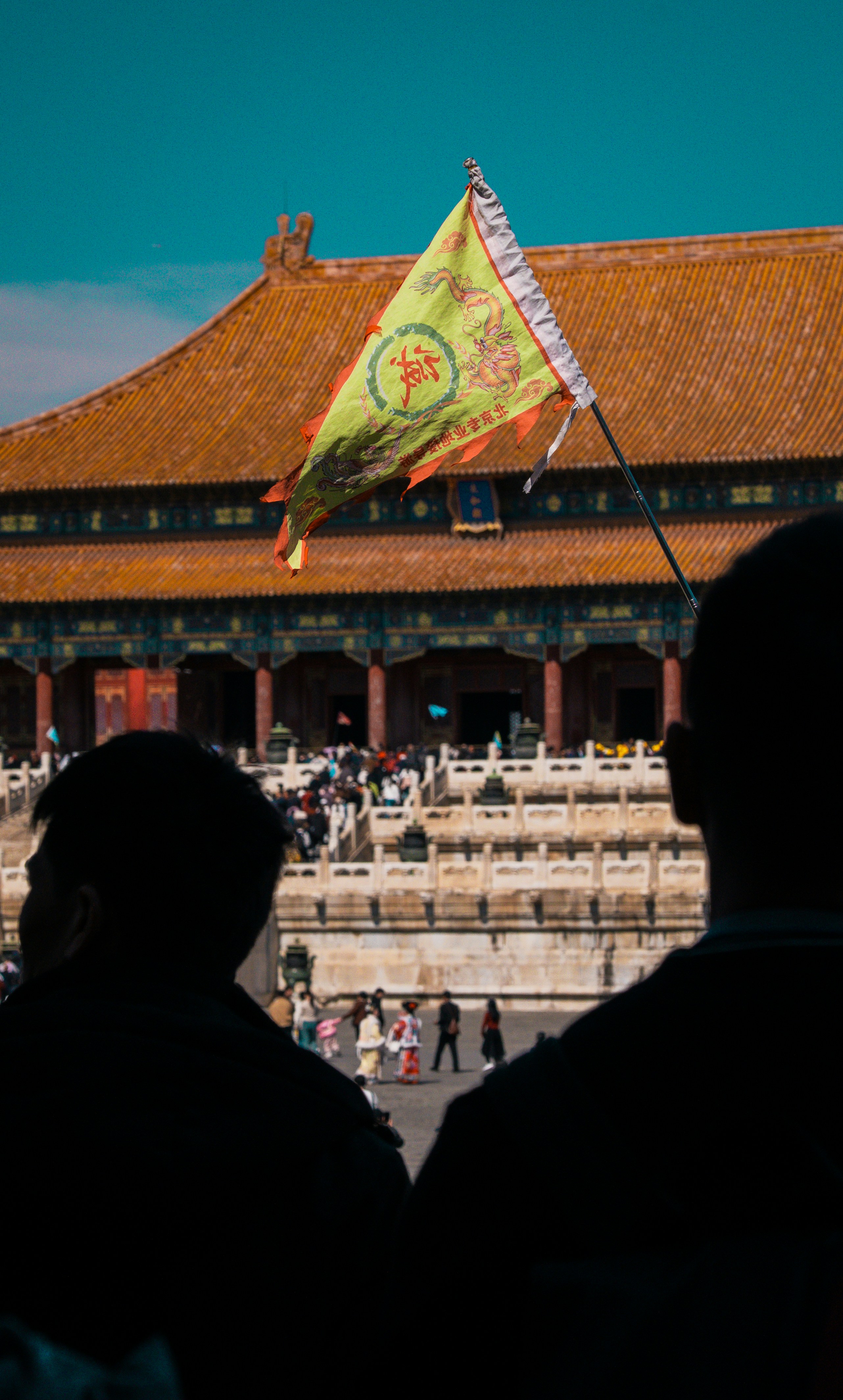 La gente observa un antiguo palacio y una bandera.