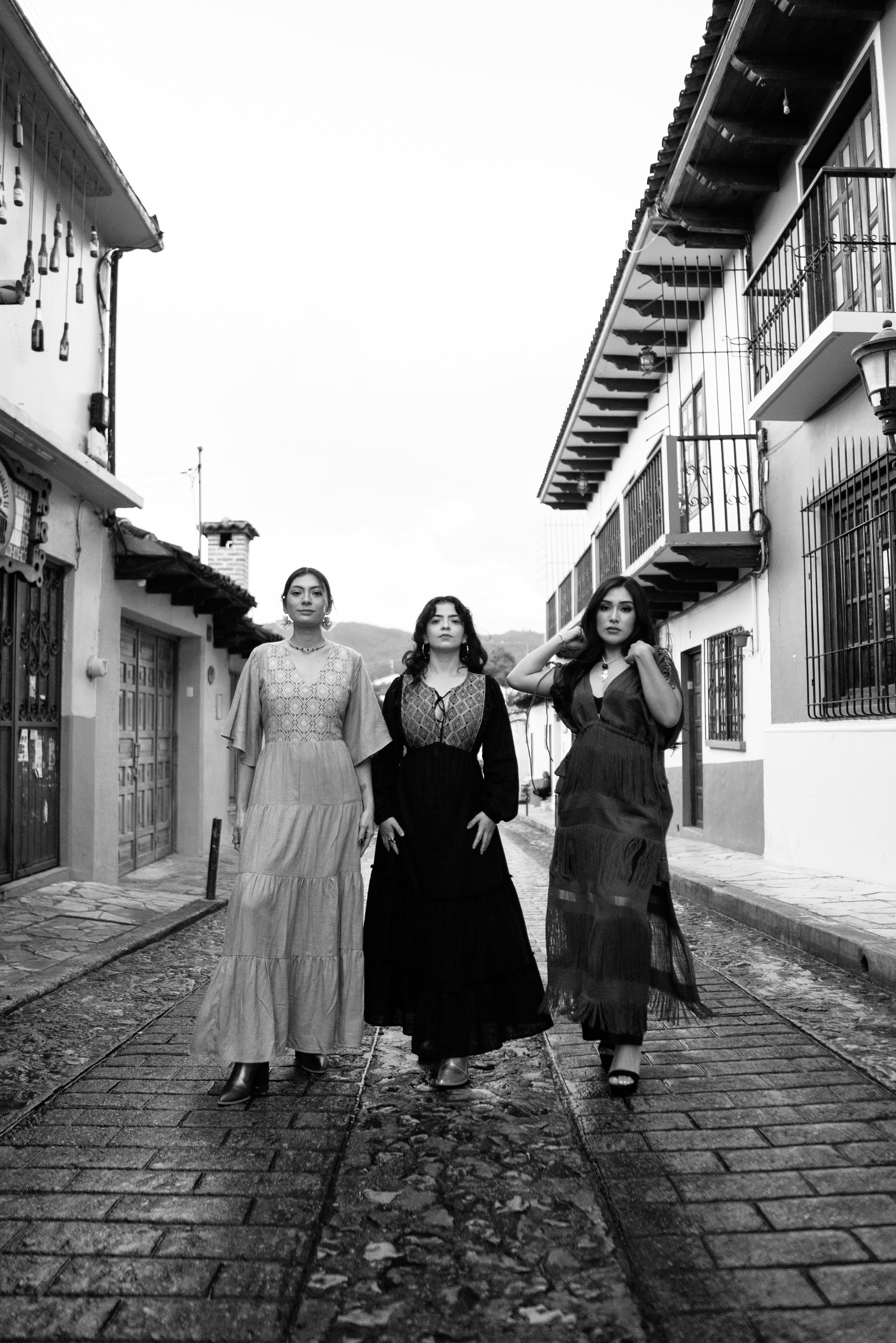 Three women walk down a cobblestone street