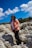 Woman poses on rocks under a bright, blue sky.