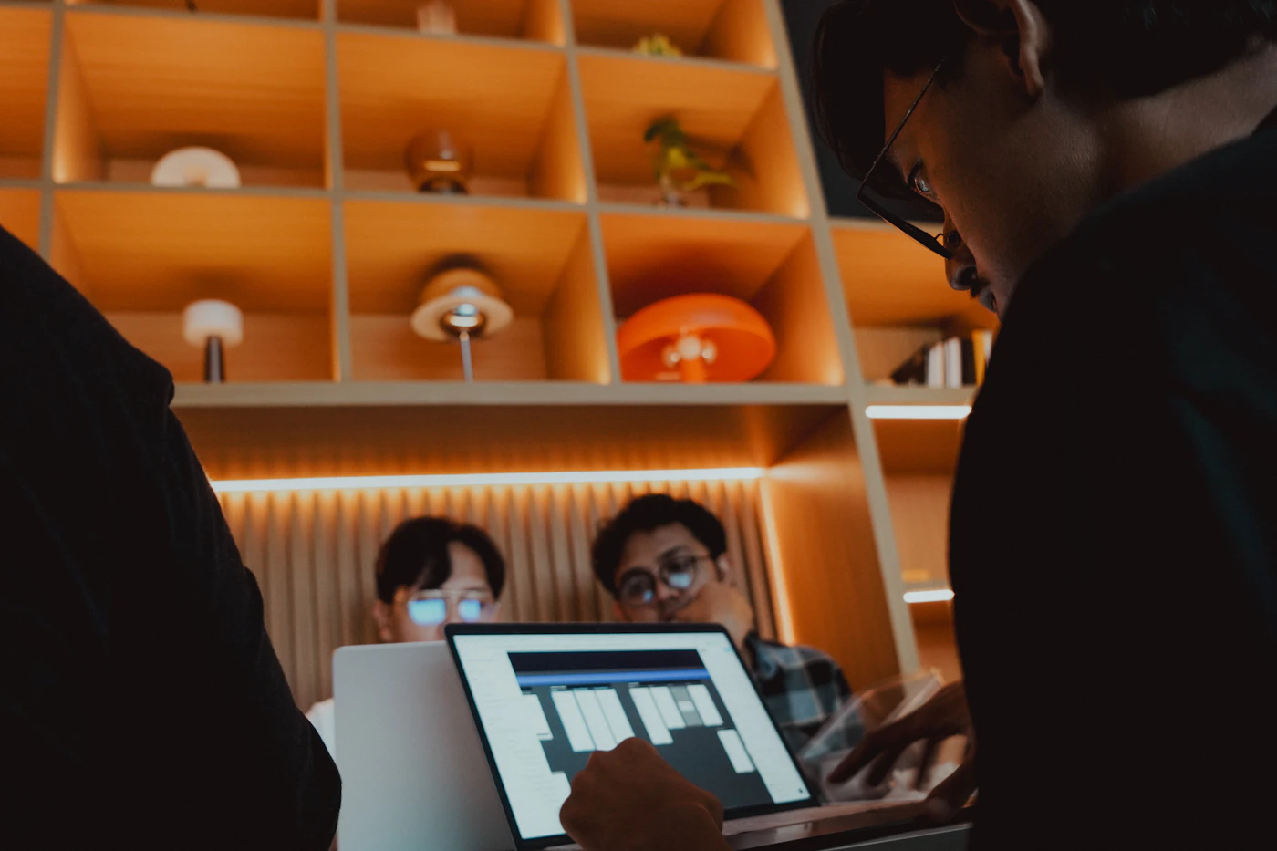 Designers collaborating around a laptop in a warm creative studio