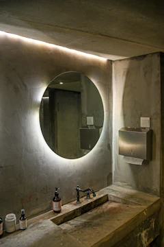 Modern bathroom features a circular, lit-up mirror.
