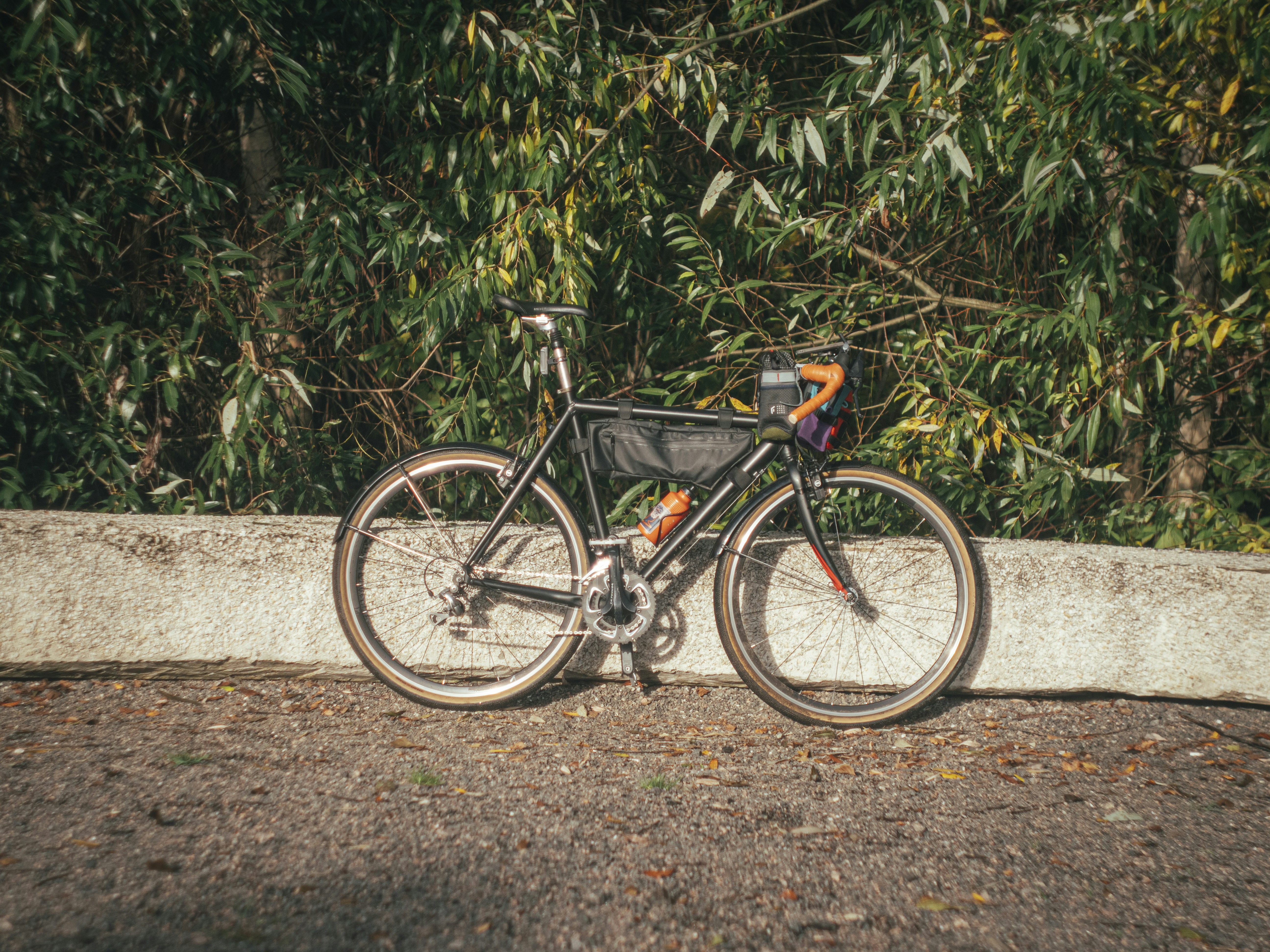 A black bicycle rests against a concrete wall.