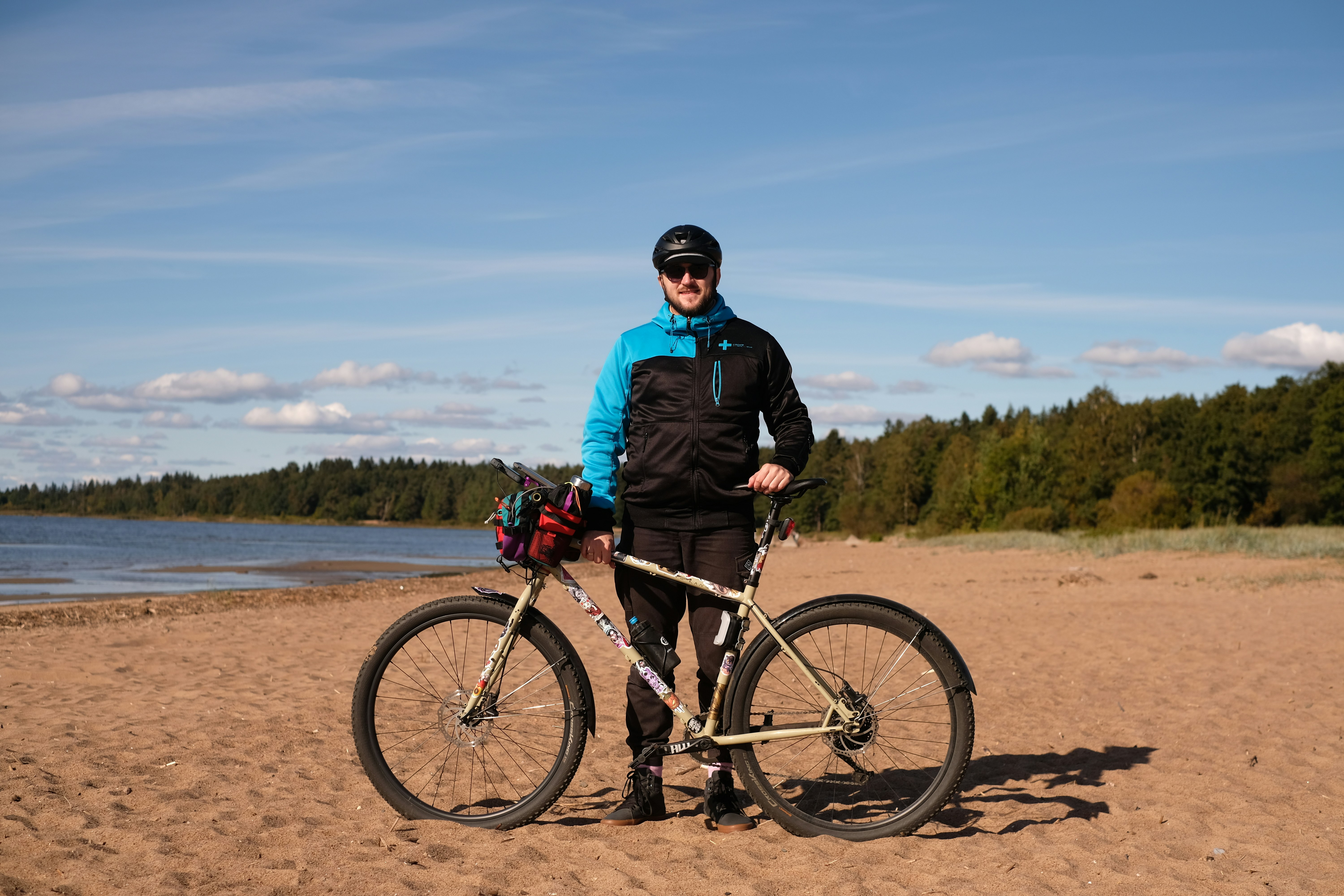 Man poses with bicycle on the beach.