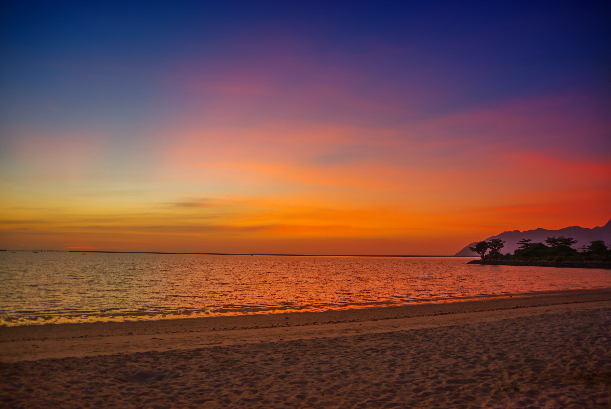 A family of four in silhouette at the water's edge, watching the sun set over the sea