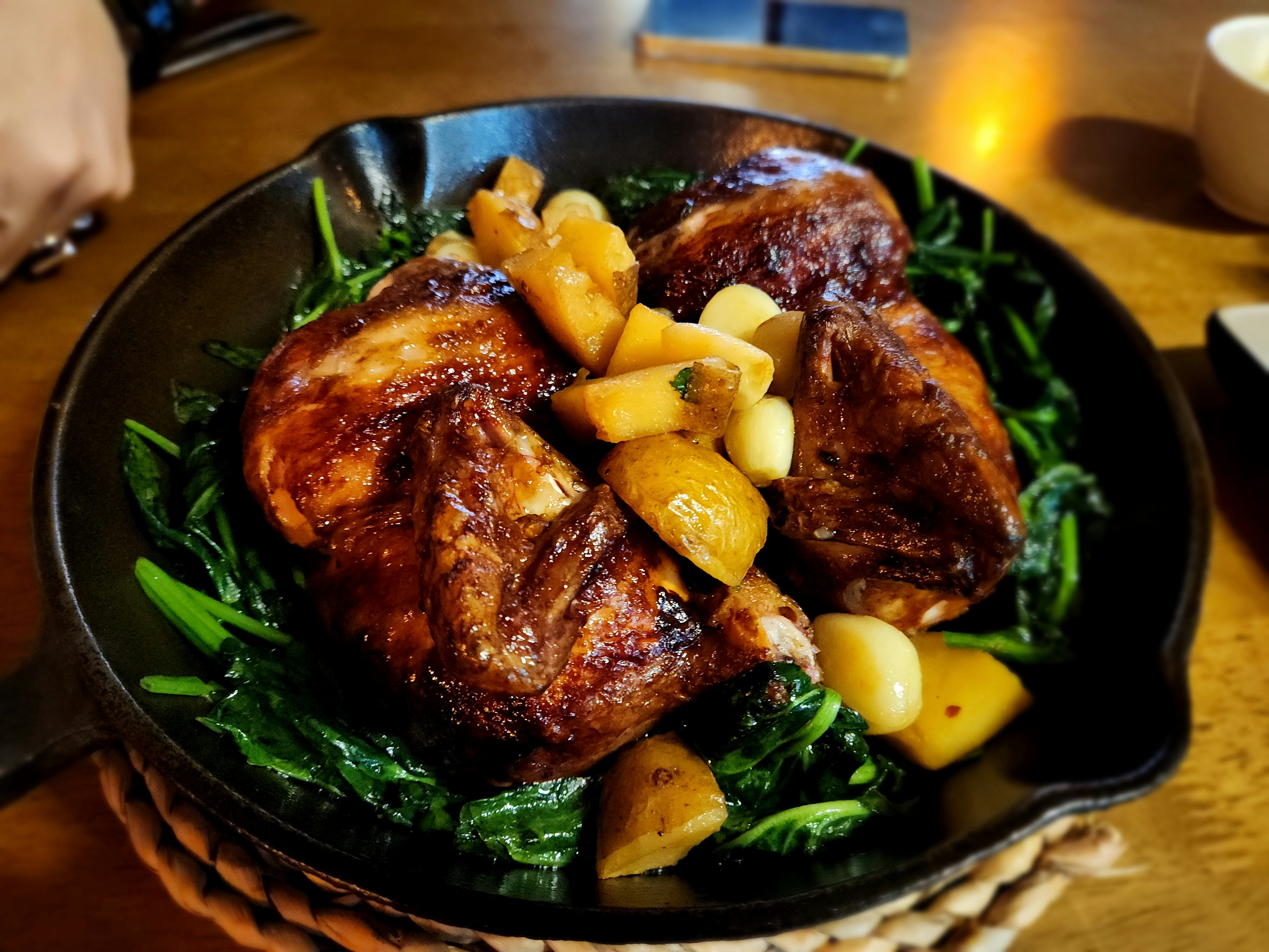 Roasted chicken and potatoes served on a bed of greens.