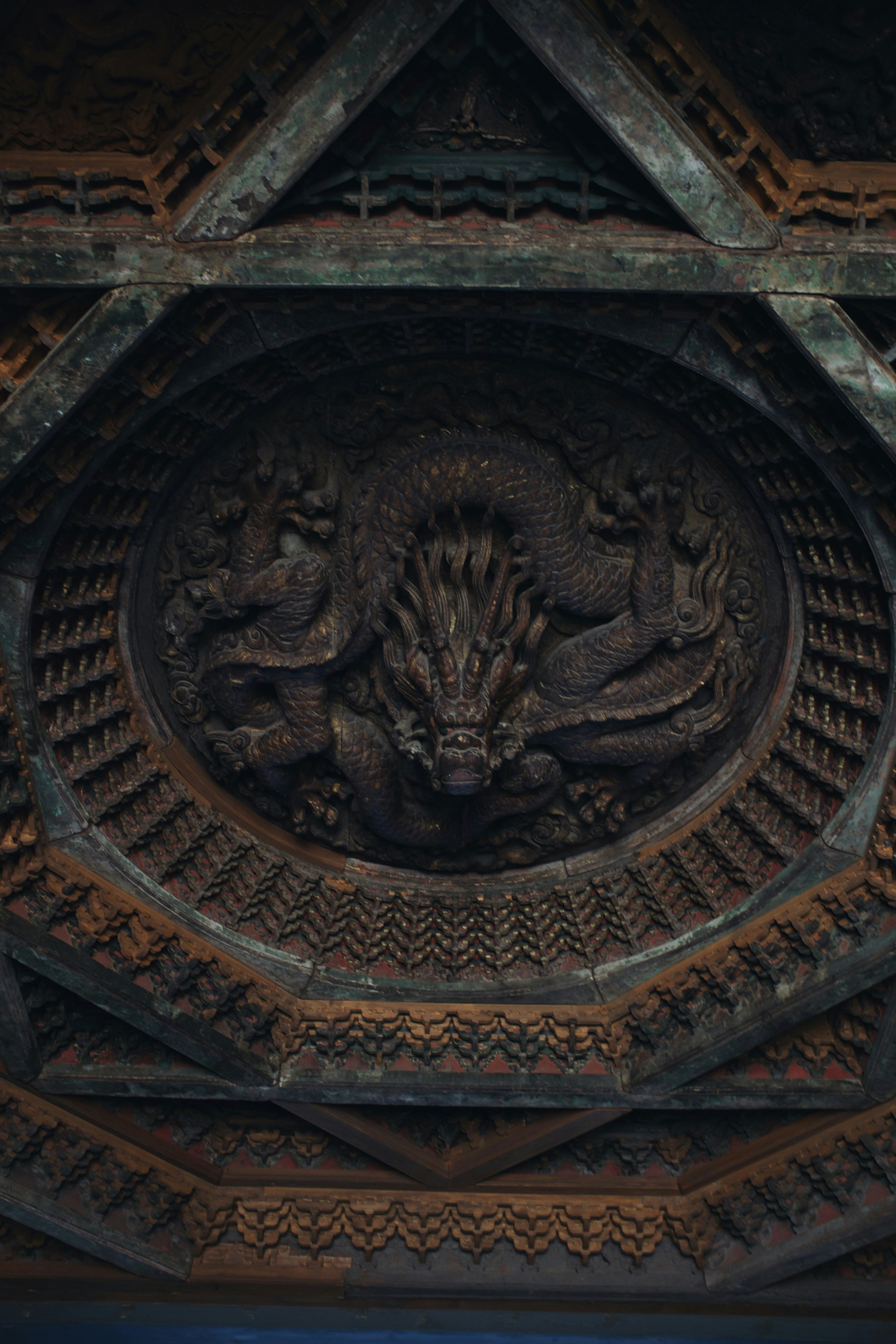 Dragon carving on an intricate wooden ceiling.