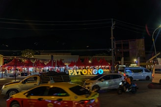 Patongo sign at night with cars.