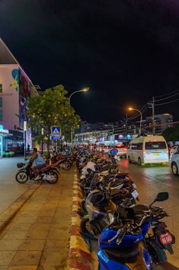 Motorbikes parked along a street at night.