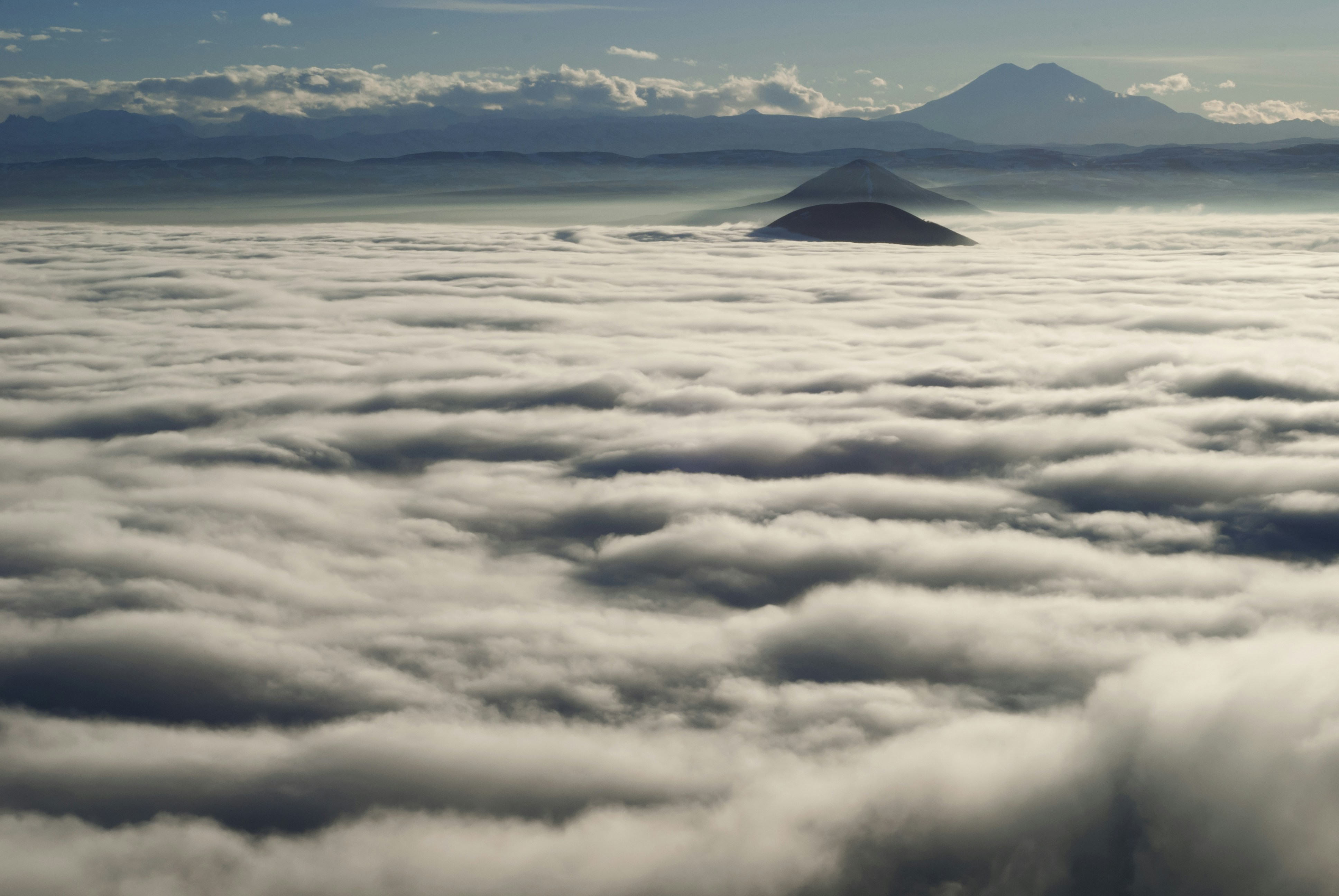 Mountains peak above a sea of clouds.