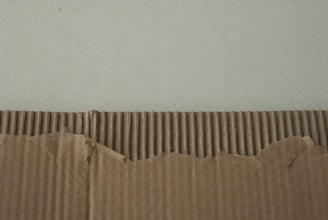Cardboard with a torn edge against a wall.