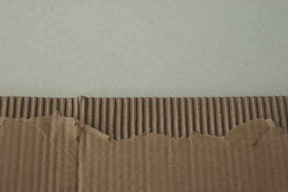 Cardboard with a torn edge against a wall.