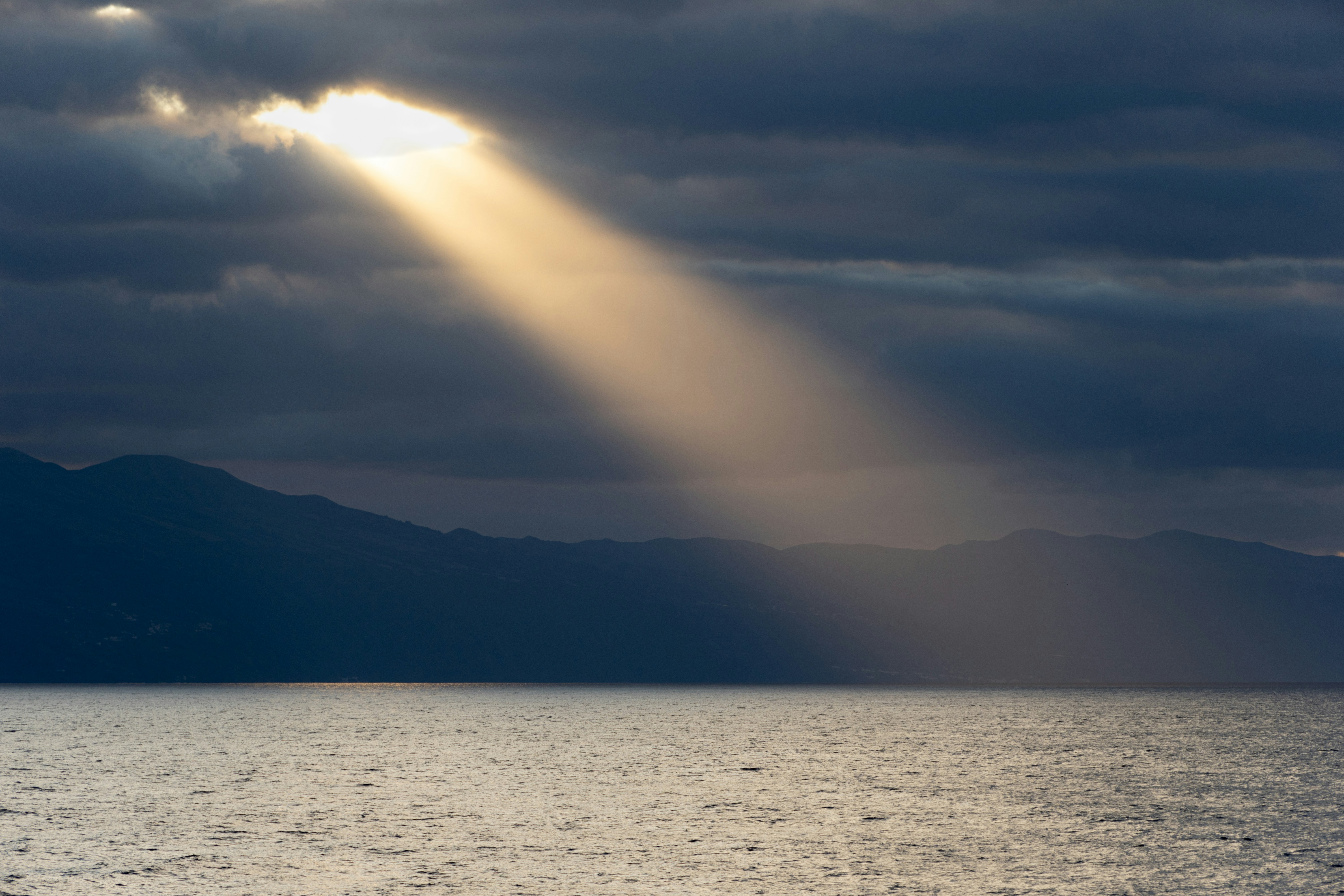 Sunlight shines through the clouds onto the water.