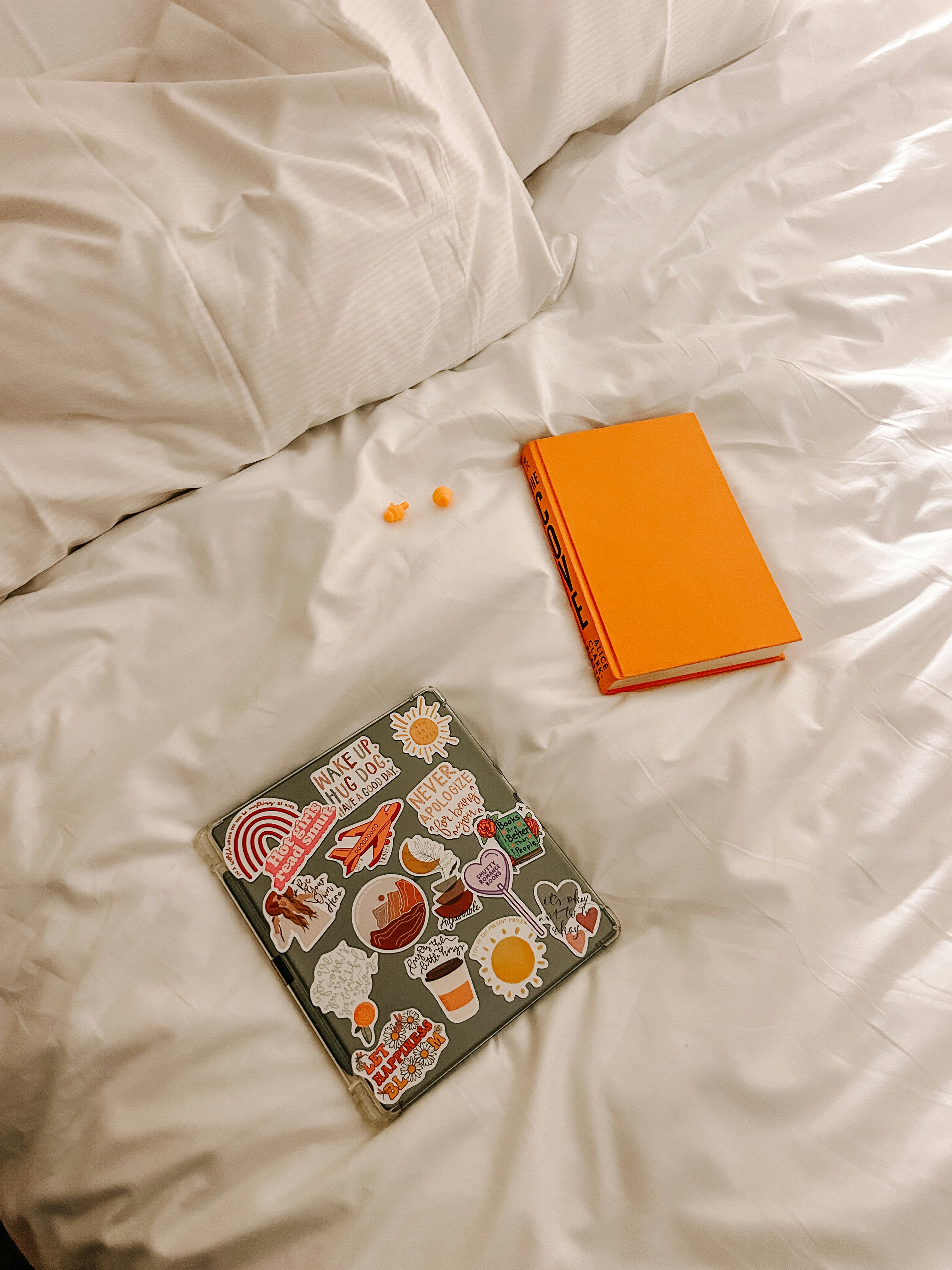 Laptop, book, and some treats on a bed.