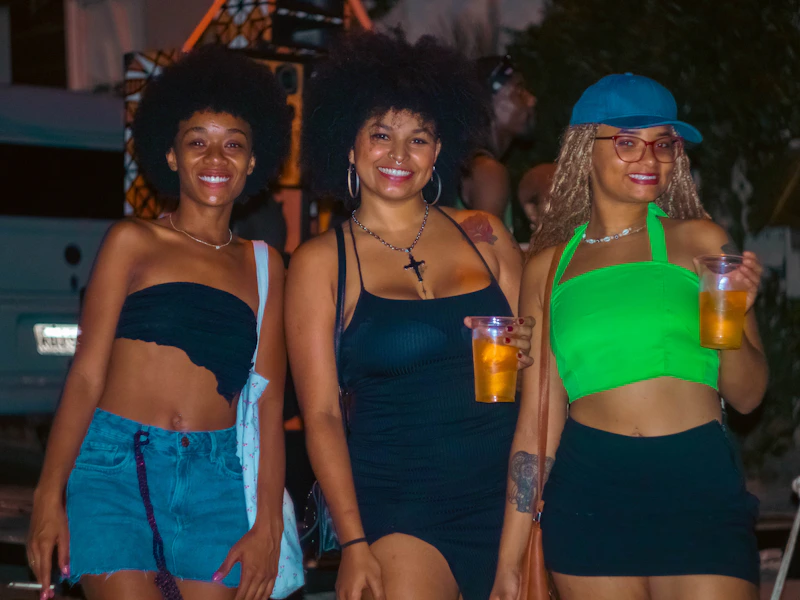 three friends smiling with drinks in hand