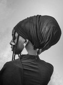 Woman wearing a headscarf and earrings in black and white.