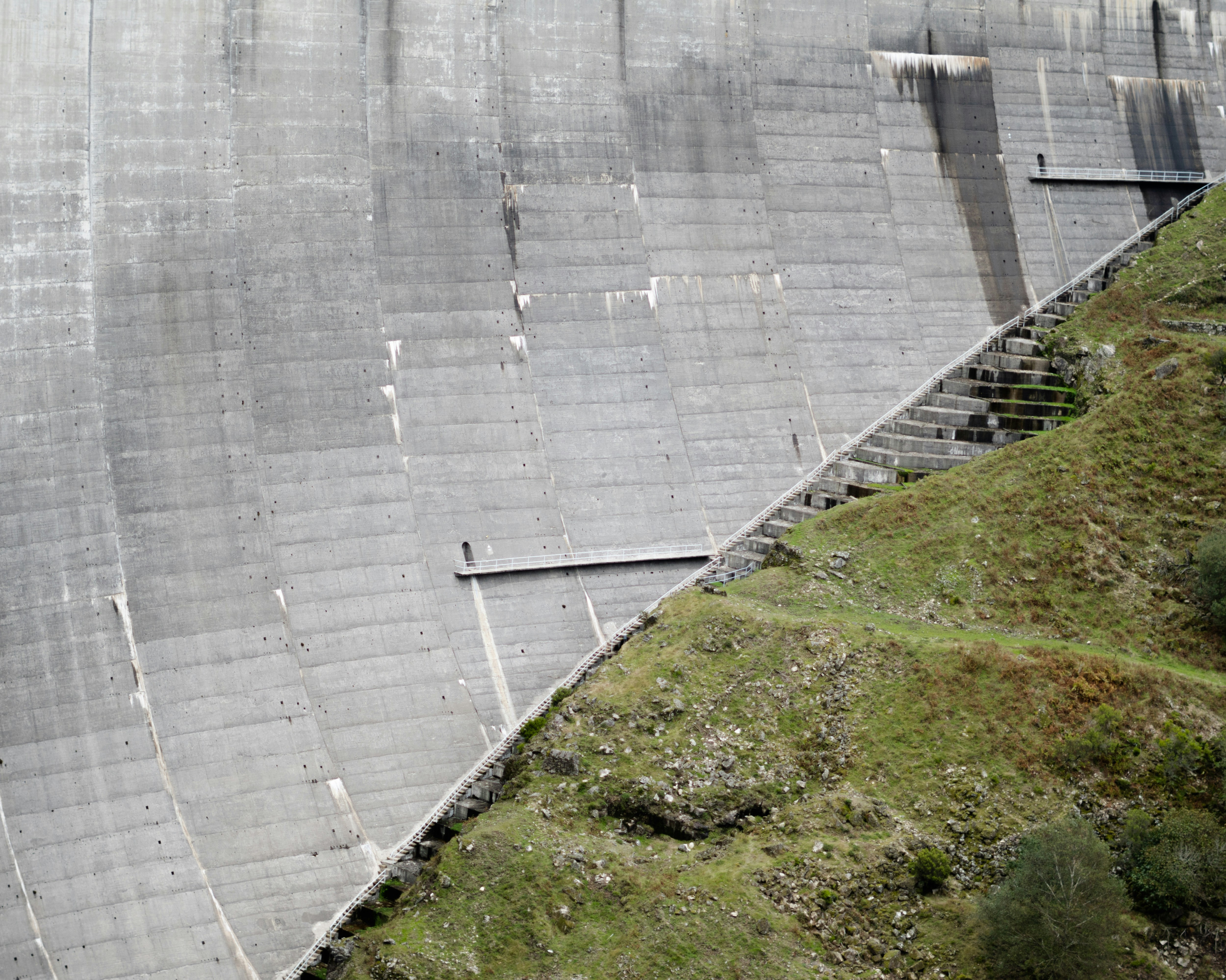 A massive concrete dam rests on a hillside.