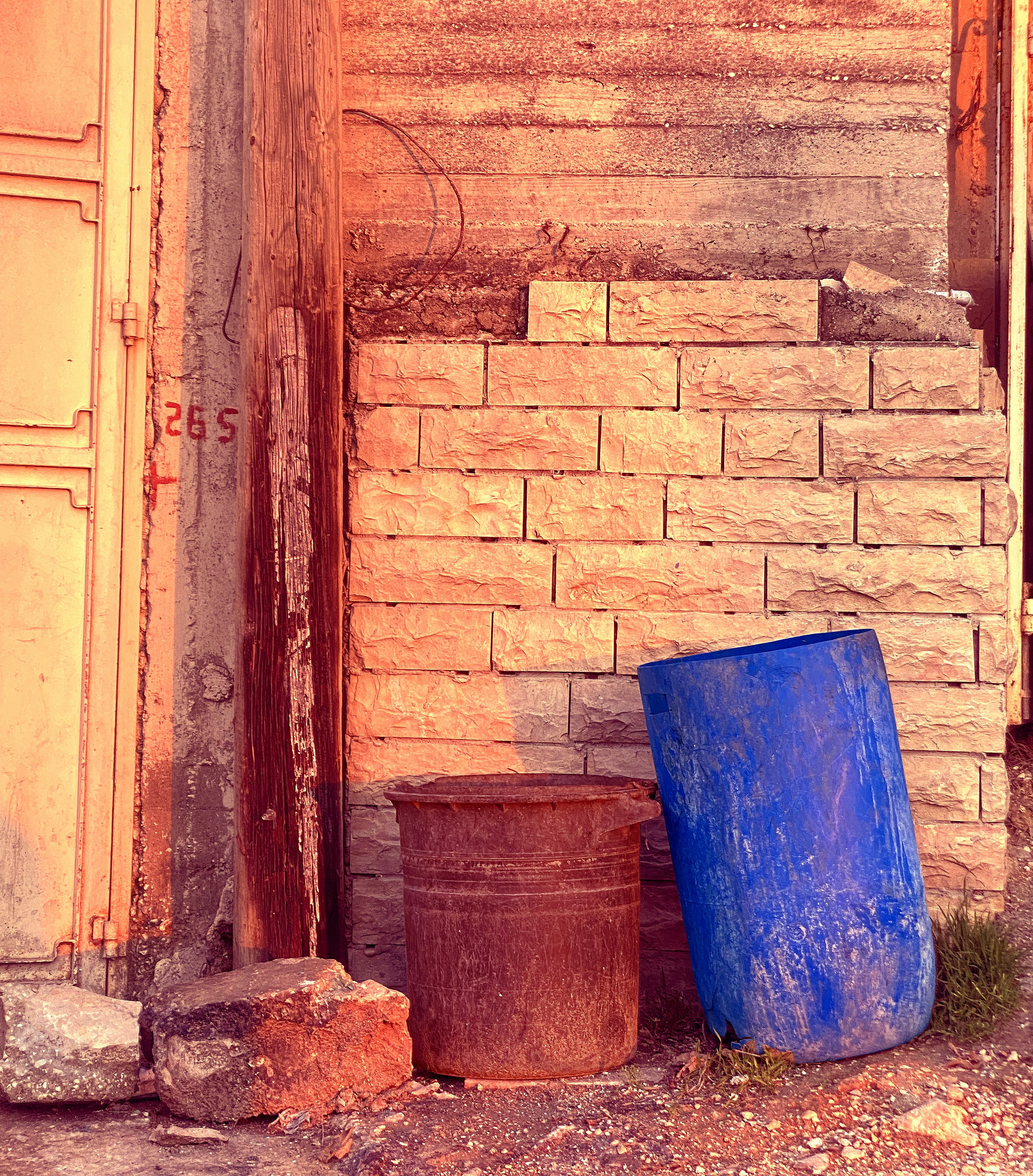 A brick wall with two barrels on the ground.